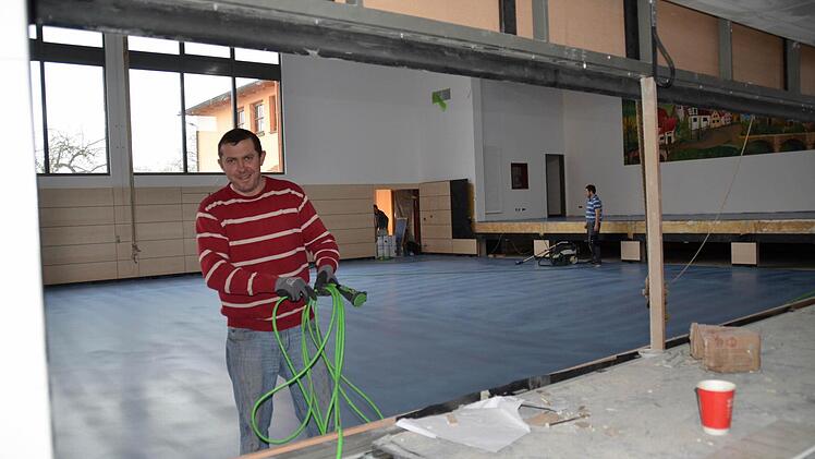 Ein Blick von der Küche in die Halle. Hier sind die Fußbodenbauer dabei, die Versiegelung des Hallenbodens vorzubereiten. Die Durchreichen im Vordergrund werden mit Rolltoren geschlossen, die auf der Hallenseite mit Prallschutz versehen sind. Foto: Kathrin Kupka-Hahn