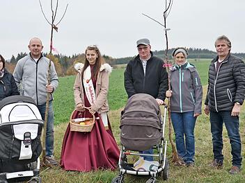 Mit Freude pflanzten die Familien Quiner (links) und Appel Apfelb&auml;ume f&uuml;r ihre Kinder Paula und Constantin. Unterst&uuml;tzt wurden sie dabei vom Vorsitzenden des Obst- und Gartenbauvereins, Ottmar L&ouml;ffler (rechts), und von der Apfelk&ouml;nigin Jessica Schnappauf (Dritte von links).  Foto: J&uuml;rgen Quiner
