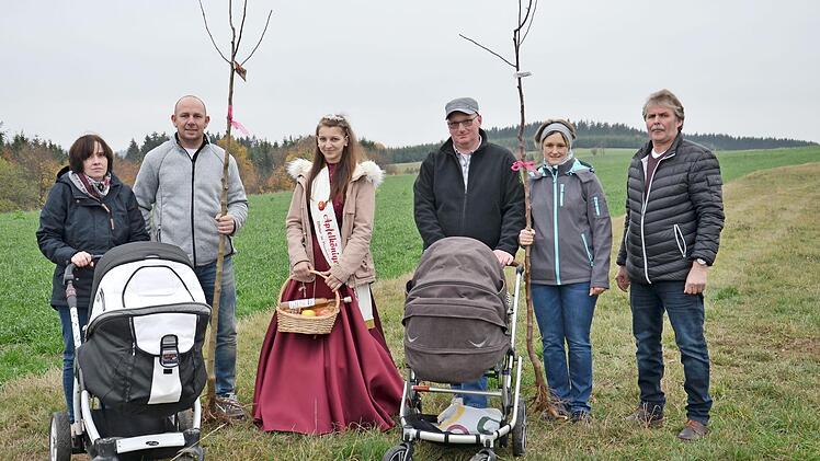 Mit Freude pflanzten die Familien Quiner (links) und Appel Apfelb&auml;ume f&uuml;r ihre Kinder Paula und Constantin. Unterst&uuml;tzt wurden sie dabei vom Vorsitzenden des Obst- und Gartenbauvereins, Ottmar L&ouml;ffler (rechts), und von der Apfelk&ouml;nigin Jessica Schnappauf (Dritte von links).  Foto: J&uuml;rgen Quiner