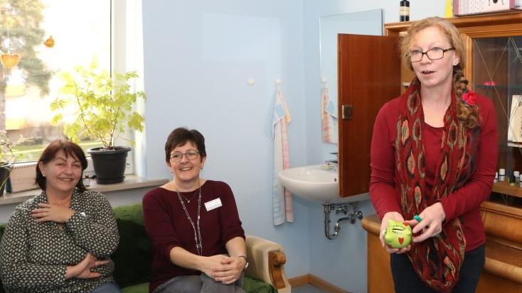 Jutta Pauly-Schroll mit dem "Aromaschweinchen", in dem Spenden gesammelt werden. Links im Bild sitzen Pflegedienstleiterin Nihal Schumm (l.) und Einrichtungsleiterin Christine Lechner.Barbara Herbst