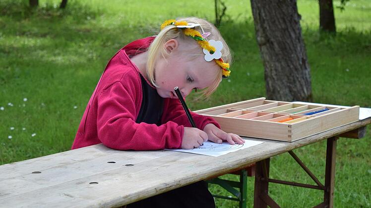 Helena, vier Jahre alt, hat sich ein Haarband gebastelt und malt nun eine Lutherrose am Basteltisch. Foto: Daniela Pondelicek