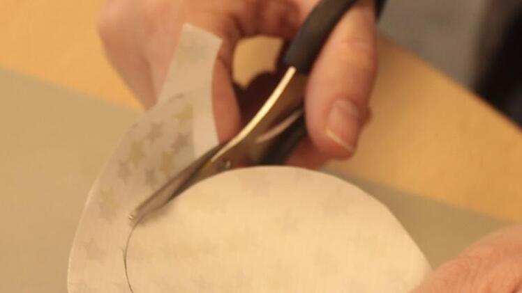 1. Nehmen Sie ein Stück Geschenkpapier und schneiden Sie mithilfe eines Glases einen Kreis. : Dann den Kreis ausschneiden.