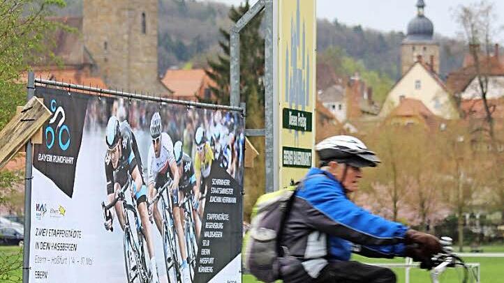 Profi trifft Hobby-Radler - im Rahmen der Bayern-Rundfahrt am Etappenziel Ebern. Unser Bild entstand gestern am Ortsrand, wo ein Plakat großformatig für das Großereignis wirbt. Foto: Eckehard Kiesewetter