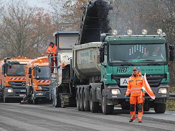 Als wäre er butterweich schabt die Fräse eine vier Zentimeter dicke Schicht vom Asphalt ab. Ein Förderband transportiert das zermahlene Material direkt auf die Ladefläche eines Lkws und zwei folgende Lastwagen säubern die Bundesstraße, so dass sie sofort wieder befahren werden kann. Während des Fräsens ist damit zunächst keine Straßensperrung auf der B279 erforderlich. Foto: Eckehard Kiesewetter