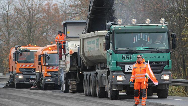 Als wäre er butterweich schabt die Fräse eine vier Zentimeter dicke Schicht vom Asphalt ab. Ein Förderband transportiert das zermahlene Material direkt auf die Ladefläche eines Lkws und zwei folgende Lastwagen säubern die Bundesstraße, so dass sie sofort wieder befahren werden kann. Während des Fräsens ist damit zunächst keine Straßensperrung auf der B279 erforderlich. Foto: Eckehard Kiesewetter