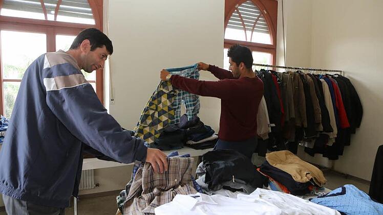 Lirim (links) und Festim sind Flüchtlinge aus Albanien. Sie dürfen sich eine Tüte mit Kleidung voll packen. Am wichtigsten: Schuhe. Foto: Barbara Herbst