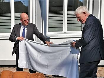 Dr. Josef Schuster (rechts), Präsident des Zentralrats der Juden in Deutschland, enthüllt gemeinsam mit Oberbürgermeister Dr. Dirk Vogel (SPD) am Platz der einstigen Synagoge die von Berufsschülerin Takayo Miura gestaltete hölzerne Gepäckrolle. Foto: Sigismund von Dobschütz
