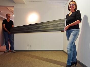 Vergangenheit und Zukunft mit der Kunst darstellen: Andrea Thema (rechts) hat das Thema der innerdeutschen Grenze in ihren Kunstwerken mit Krakelees und Schleifpapier verarbeitet. Im Hinblick auf die Wiedervereinigung ist das Werk "Der lange Weg" entstanden. Es stellt den Weg dar, den die Gesellschaft seither gemeinsam gegangen ist und noch weiter gehen wird. Foto: Jphanna Eckert