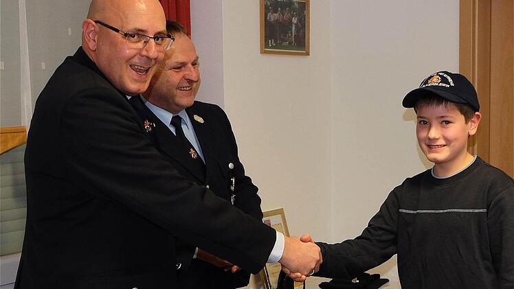 Kommandant Florian Hluchy und Vorsitzender Lothar Haas begrüßten per Handschlag Philipp Zeller bei der Jugendfeuerwehr. Foto: Gerd Schaar