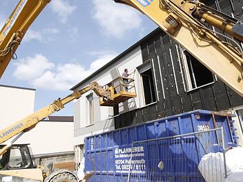 Hebebühnen bringen die Arbeiter in die Höhe. Dort tragen sie die äußere Hülle der Gebäudewände ab. Fotos: Josef Hofbauer