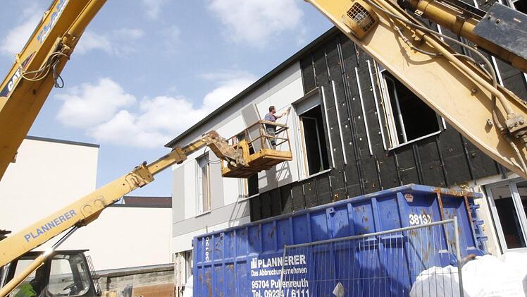 Hebebühnen bringen die Arbeiter in die Höhe. Dort tragen sie die äußere Hülle der Gebäudewände ab. Fotos: Josef Hofbauer