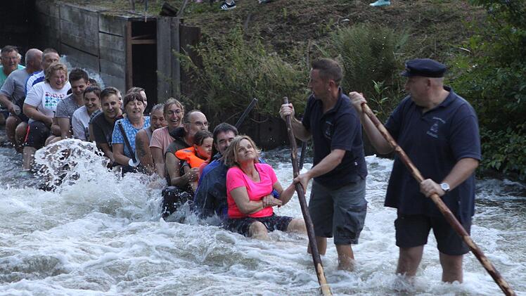 Die Flößer stehen knöcheltief im Wasser - und auch die Besucher bleiben nicht trocken. Foto: Michael Wunder
