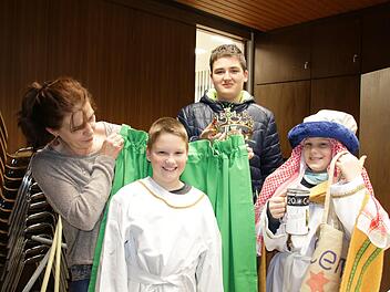 Gabi Müller (links) betreut seit Jahren die Sternsinger-Aktion in Hausen. Hier probiert sie gerade, ob Luis und Samuel die Gewänder aus dem Fundus passen, hinten hält Nico die Krone bereit. Foto: Ralf Ruppert