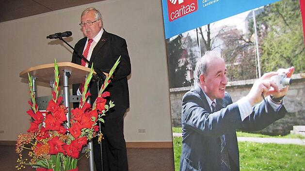 Caritasdirektor Gerhard Öhlein bei seiner Laudatio für den scheidenden Coburger Kreis-Caritas-Geschäftsführer Richard Reich, der während der Reden auf dem Plakat rechts stets präsent war.  Foto: Martin Koch