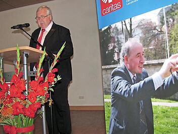 Caritasdirektor Gerhard Öhlein bei seiner Laudatio für den scheidenden Coburger Kreis-Caritas-Geschäftsführer Richard Reich, der während der Reden auf dem Plakat rechts stets präsent war.  Foto: Martin Koch