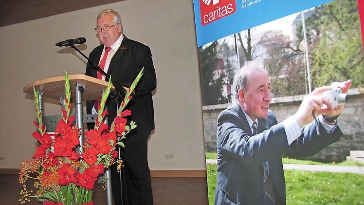 Caritasdirektor Gerhard Öhlein bei seiner Laudatio für den scheidenden Coburger Kreis-Caritas-Geschäftsführer Richard Reich, der während der Reden auf dem Plakat rechts stets präsent war.  Foto: Martin Koch