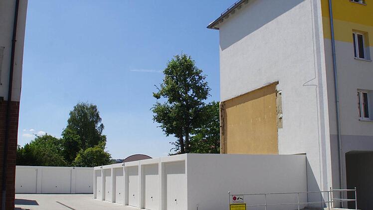 Eine gepflasterte Einfahrt mit einer Reihe Garagen, der Blick an einem sanierten Wohngeb&auml;ude vorbei auf den blauen Himmel und die B&auml;ume. W&auml;re da nicht ein Einschnitt an der wei&szlig;en Fassade zu erkennen, k&auml;me man kaum auf den Gedanken, dass dort in der Kaulangerstra&szlig;e fr&uuml;her ein Lebensmittelmarkt zu finden war. Das Gesch&auml;ft wurde komplett abgerissen. Foto: Marco Mei&szlig;ner