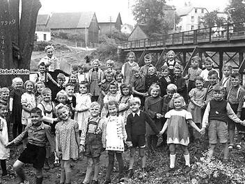 Der Unterricht im Freien erfreute 1949 die Mainleuser Erstklässler - darunter Bärbel Schülein, geborene Kohl (mit Pfeil), die  das Foto   zur Verfügung stellte. Im Hintergrund die damalige eiserne Mainbrücke, die jetzt saniert worden ist und am Freitag wieder für den Verkehr freigegeben wird. Foto: privat