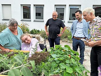 Geschäftsführerin Ute Häußer (r.), Regionaldirektor Michael Götz (2. v. r.) und Bildungsleitung Siegfried Aiglstorfer (Mitte) schauen bei der Ernte zu.