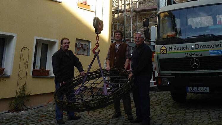 Uwe Koch von der Bauverwaltung der Stadt Kronach, Markus Schäuble von der Interessengemeinschaft Obere Stadt und Stadtrat Wolfgang Hümmer von der gleichnamigen Stahl- und Metallbaufirma haben das Grundgerüst für ein neues Storchennest am Haken. Foto: Oliver Martin