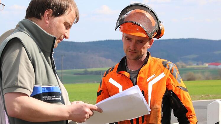 Förster Joachim Dahmer hat extra eine Übersicht vom Landratsamt bekommen, wann welcher Bus an der B286 verkehrt. Hier erklärt er Forstwirt Andreas Bauer, wann der nächste kommen wird. Foto: Kathrin Kupka-Hahn