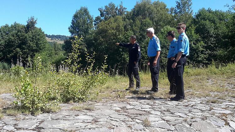 Feuerwehr-Chef Frank Kuchler  (hinten links) weist auf die Zisterne im Bereich des Diesbachs hin. Insgesamt fünf dieser Becken für den Wasservorrat gibt es auf dem Truppenübungsplatz Wildflecken.   Foto: Rolf Pralle