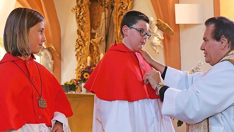 Pfarrer Chelkowski hängte den beiden neuen Ministranten Paula Friedrich (links) und Raffael Senger die Ministrantenkreuze um.  Foto: Klemenz