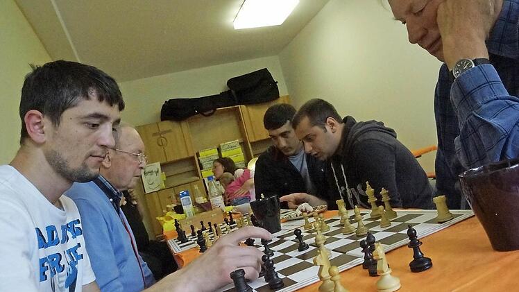 Norbert Binder (Zweiter von links) und Hans Roth (rechts) spielen mit Asylbewerbern Schach.