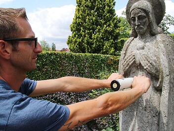 Friedhofsmitarbeiter Daniel Reheusen prüft einen Grabstein auf seine Standfestigkeit. Foto: Sebastian Schanz