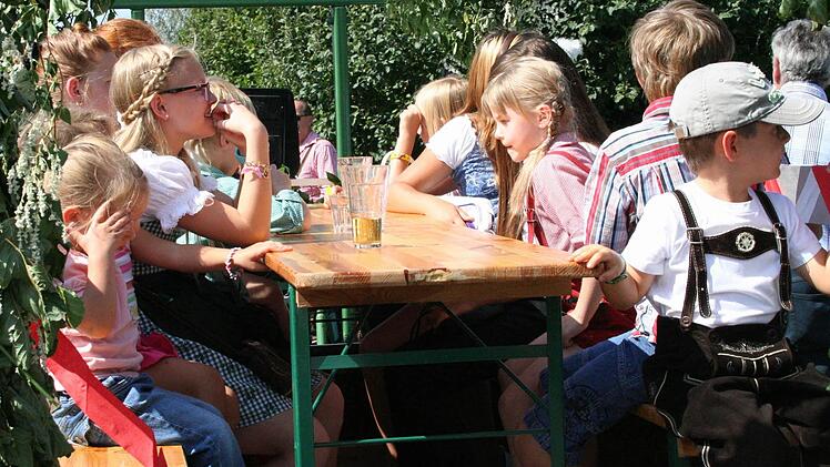 Die Kinder machen es sich am Biertisch auf einem der Wagen bequem, während die Erwachsenen ihren Umtrunk genießen.