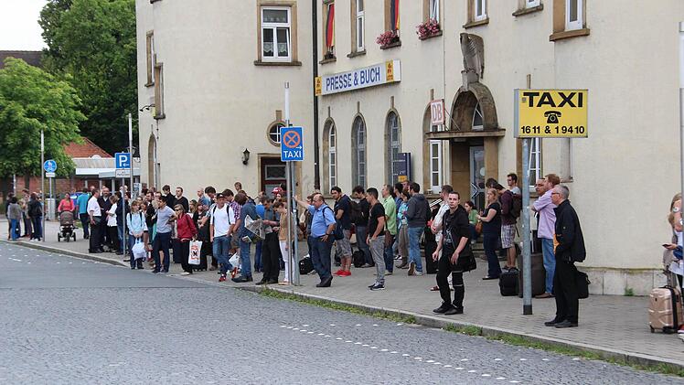 Die verhinderten Bahnreisenden warten vor dem Bahnhof auf die Busse.
