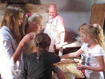 Konzentriert waren die kleinen Pizzabäcker bei der Sache. Auf großen rechteckigen Backblechen belegten sie die Pizza, beobachtet von Bäckermeister Reinhold Vornwald. Foto: Irene Kirchner