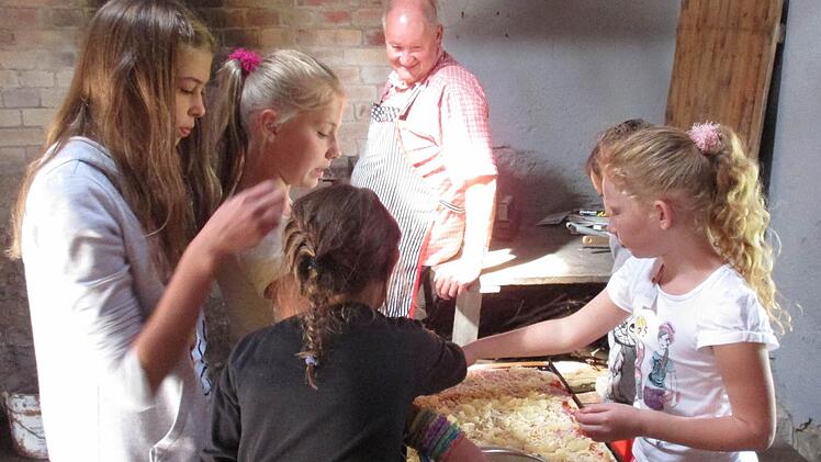 Konzentriert waren die kleinen Pizzabäcker bei der Sache. Auf großen rechteckigen Backblechen belegten sie die Pizza, beobachtet von Bäckermeister Reinhold Vornwald. Foto: Irene Kirchner