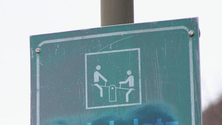 Der Hinweis für Kinder unter 14 Jahre ist noch sichtbar, aber die Verbotshinweise für Radfahrer, Fußballspielen und Hunde sind auf beiden Seiten überschmiert.Geiling