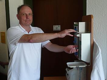 Josef Woidich ist Krankenhaushygieniker am Klinikum Lichtenfels. Vor einem Patientenzimmer mit Aufkleber an der Tür, der auf ein Risiko hinweist, betätigt der Oberarzt den Spender mit dem Desinfektionsmittel. Fotos: Ramona Popp