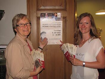 Christine Spiller (rechts) und Brigitte Maisch (links) rühren die Werbetrommel für das Doppeljubiläum von Stadtbücherei und Puppenmuseum am Samstag, 8. Juli. Foto: Martin Koch