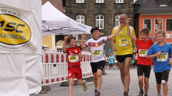 L&auml;chelnd &uuml;berquert der sportliche Landrat Christian Mei&szlig;ner zusammen mit einigen Kindern nach beendetem 5,2-Kilometer-Lauf die Ziellinie. Foto: Mario Deller