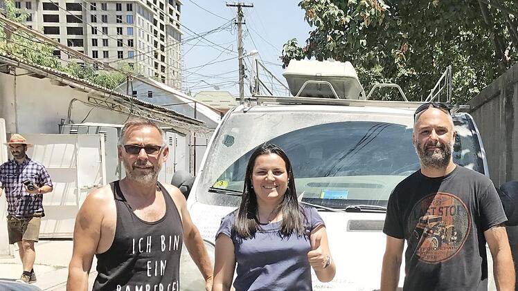 Wolfgang Dusold (l.) und Alexander Brehm mit der Caritas-Büroleiterin Parwina Tadjibaewa vor dem Opel-Bus Foto: p