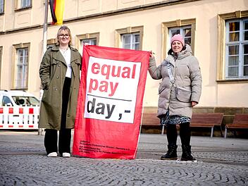 Elena H&uuml;mmer und Nina K&ouml;hler von der Gleichstellungsstelle hissen die Fahne zum Equal Pay Day vor dem Rathaus Maxplatz.