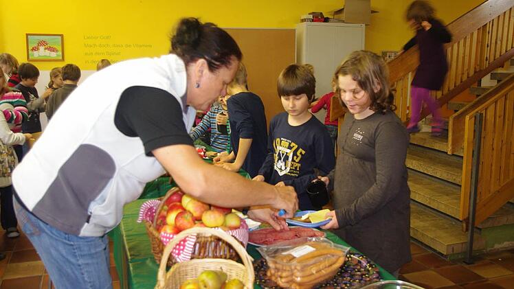 Lukas Häfner, Fabian Höfner und Enja Wiesmann  (von links)  greifen bei der Pausenbrot-Aktion tüchtig zu. Mit im Bild ist (links) Rektorin Barbara Fößel. Foto: Heike Schülein