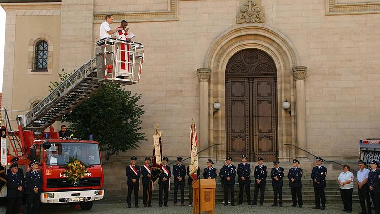 Im doppelten Sinne von oben kam der Segen für das neue Drehleiter-Fahrzeug der Feuerwehr Eltmann, denn Pfarrer Mark Odah stieg mit Bürgermeister Michael Ziegler für die Segnung in den Korb der Leiter. Dort segnete der Seelsorger das neue Auto vor der Eltmanner Kirche.  Fotos: sw