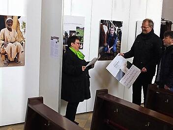Pastoralreferentin Birgitta Staufer-Neubauer, Regionaldekan Thomas Teuchgr&auml;ber und Gemeindereferent Martin F&ouml;rtsch betrachten interessiert den Flyer zur Ausstellung "Mensch.Macht.Milch".