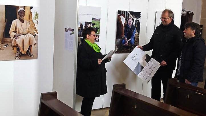 Pastoralreferentin Birgitta Staufer-Neubauer, Regionaldekan Thomas Teuchgr&auml;ber und Gemeindereferent Martin F&ouml;rtsch betrachten interessiert den Flyer zur Ausstellung "Mensch.Macht.Milch".
