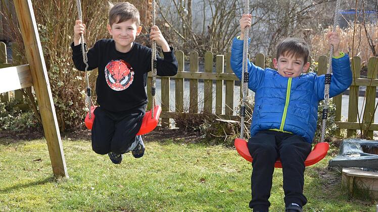 Bei schönem Wetter schaukeln die Jungen im Garten. Aber sie vermissen ihre Freunde.