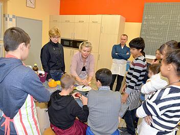 Verständigung durch Zeigen und Nachmachen: Die Lehrer Juliette Kemmer, Vally Ölschlegel und Benno Hoch (von links) bereiten Obstsalat mit den Kindern von Asylbewerbern zu. Foto: Ronald Rinklef