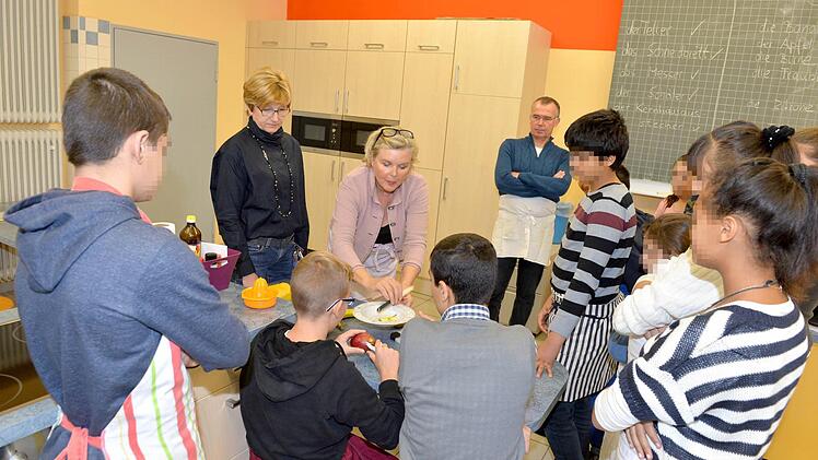 Verständigung durch Zeigen und Nachmachen: Die Lehrer Juliette Kemmer, Vally Ölschlegel und Benno Hoch (von links) bereiten Obstsalat mit den Kindern von Asylbewerbern zu. Foto: Ronald Rinklef