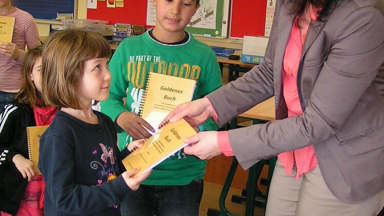 Rektorin Andrea Kohl gibt Linda das "Goldene Buch. Nikos hat seines schon. Fotos: Amon