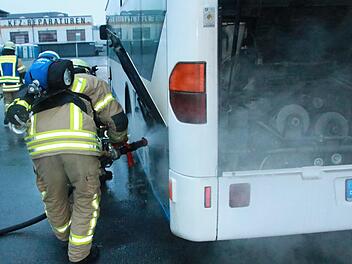Die Feuerwehrleute beim Löschen der Flammen im Motorraum des Busses   Foto: Matthias Einwag