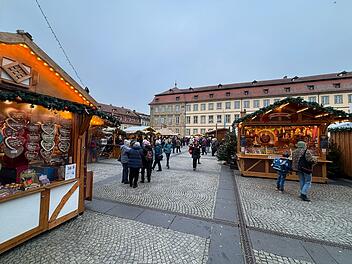 Weihnachtsmarkt in Bamberg mit festlich geschmückten Buden, geschäftigen Besuchern und traditionellen Lebkuchenherzen. Atmosphäre voller Vorfreude und Genuss.