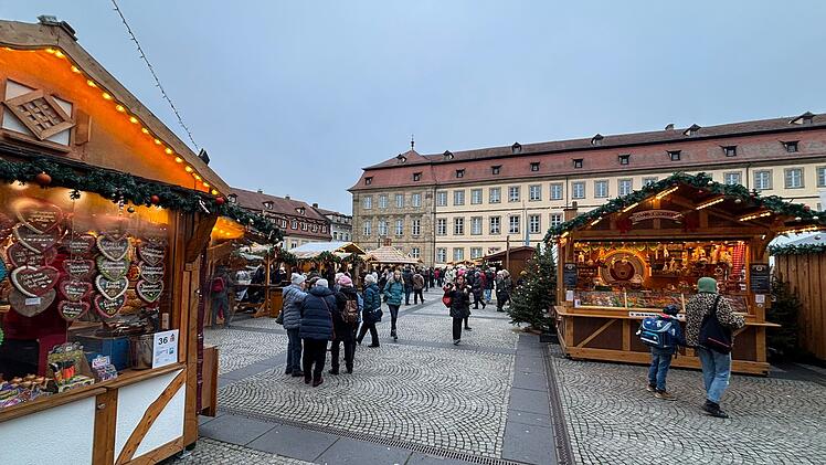 Weihnachtsmarkt in Bamberg mit festlich geschmückten Buden, geschäftigen Besuchern und traditionellen Lebkuchenherzen. Atmosphäre voller Vorfreude und Genuss.